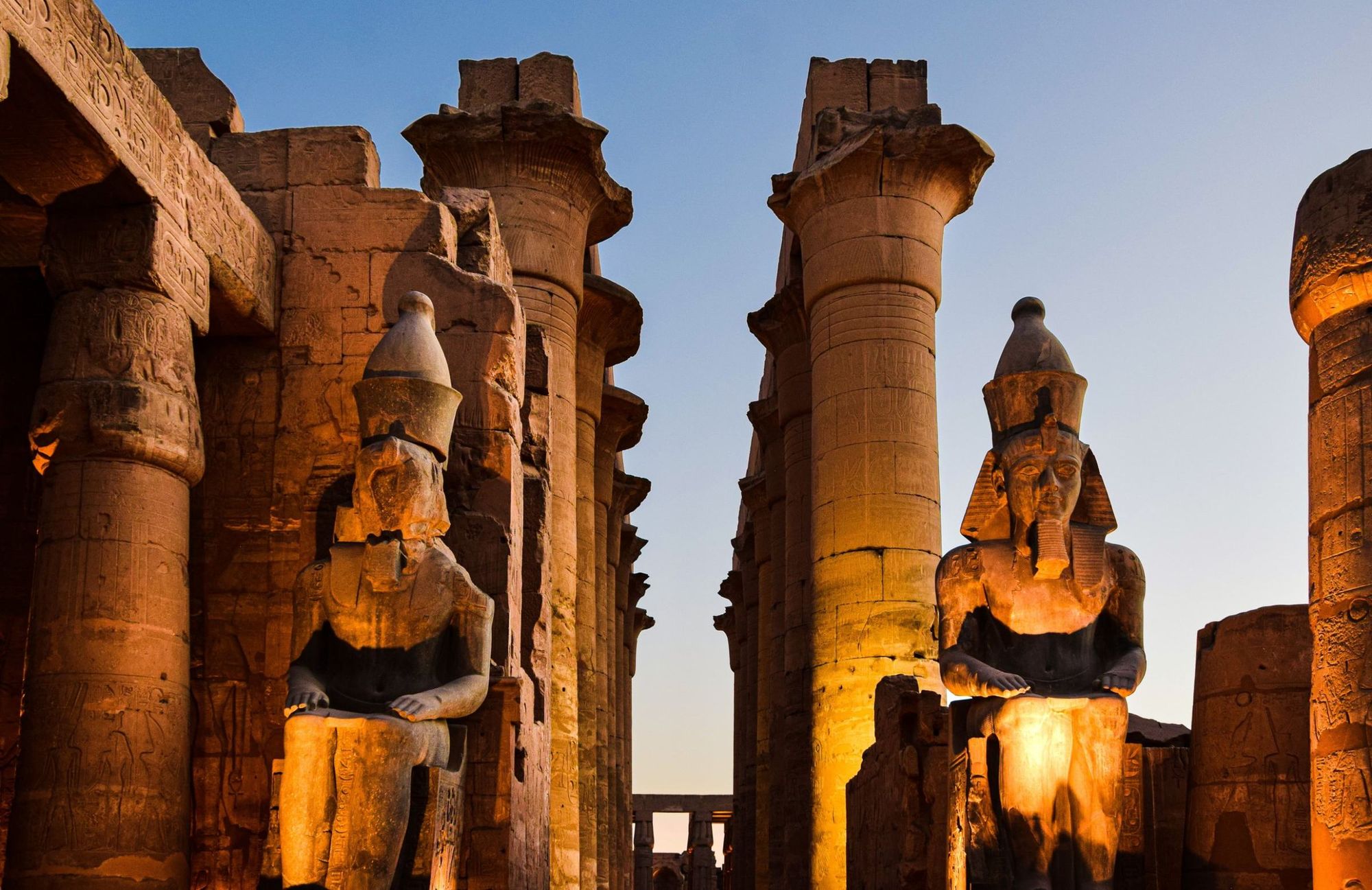 Statues of Ramses II among the columns of Luxor Temple at dusk